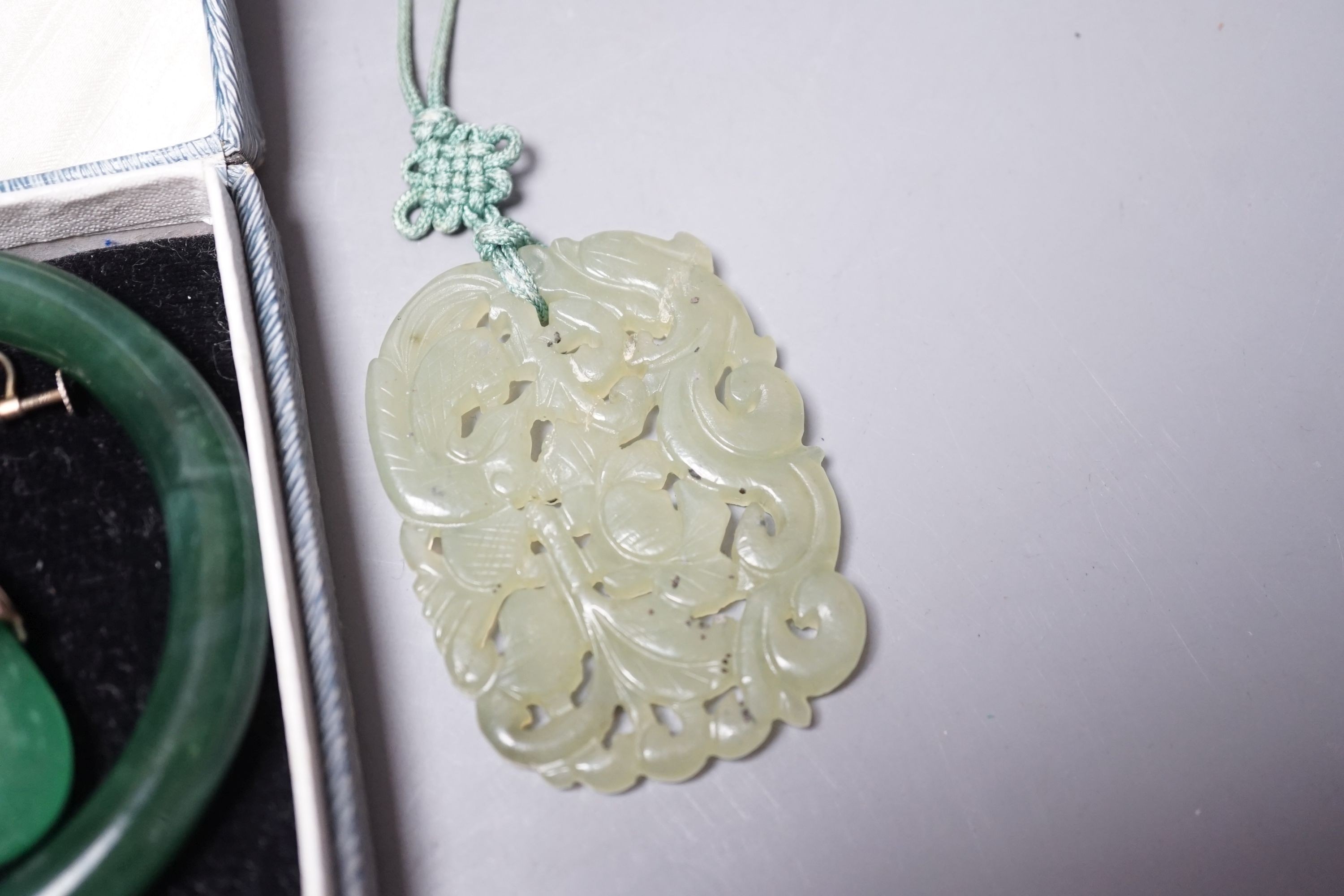 A Chinese carved bowenite jade pendant, a pair of green paste earrings and a green paste bangle.